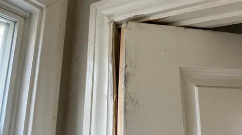 Interior door that no longer fits its frame, with an uneven gap along the top corner